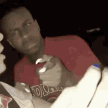 a man in a red shirt is holding a bottle of toothpaste in his hands .