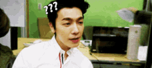 a man with a question mark on his forehead is sitting at a desk .