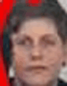 a close up of a person 's face with a red background and a blurry background .