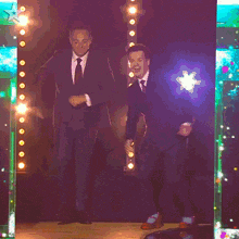 two men in suits and ties are dancing in front of a star