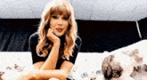 taylor swift is sitting on a couch with a cat on her lap .
