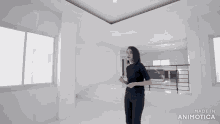 a woman stands in an empty room with the words made in animatica on the bottom right