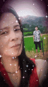 a woman in a red tank top stands in front of a green field