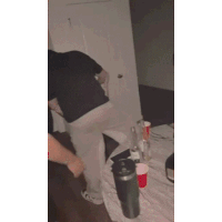 a man is standing on a bed in a room with bottles and cups .