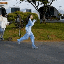 two women are running down a street in front of a house .