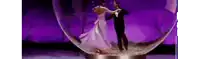 a man and a woman are dancing in a snow globe on a stage .
