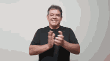 a man wearing a black shirt is clapping his hands and smiling
