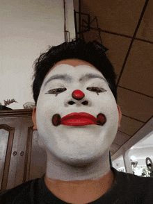 a man with his face painted like a clown with red lips