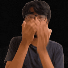 a man wearing glasses covers his face with his hands