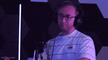 a man wearing headphones and glasses is sitting in front of a microphone .