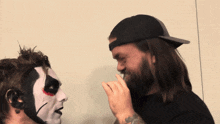 a man with a beard is touching another man 's face with his hand
