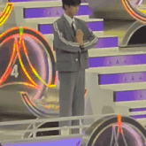 a man in a suit and tie is standing in front of a stage with the number 4