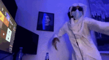 a person wearing a mask and sunglasses is dancing in front of a computer monitor