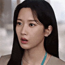 a close up of a woman 's face with a surprised look on her face and a necklace around her neck .