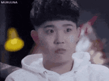 a man in a white hoodie is making a funny face and looking at the camera .