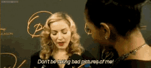 a woman is talking into a microphone while another woman says " don 't be taking bad pictures of me "