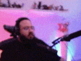 a man with a beard is sitting in a chair in front of a microphone .
