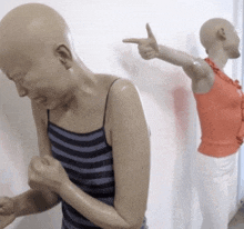 a bald woman in a striped tank top is pointing at another bald woman in a red top