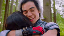 a man and a woman are hugging in the woods .
