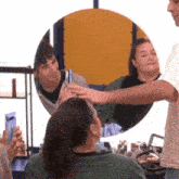 a man is touching a woman 's head in front of a mirror