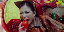 a woman in a cat costume is eating a tomato in front of a colorful background .