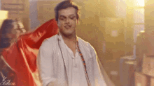 a man in a white shirt is dancing with a red cloth behind him .