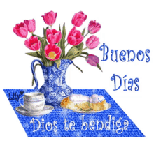a blue vase with pink flowers sits on a blue table with a cup of coffee