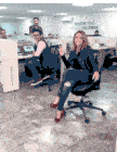 a woman is sitting in an office chair with a sign that says pasion por lo que hacemos behind her