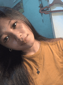 a woman wearing a necklace with a cross on it looks at the camera