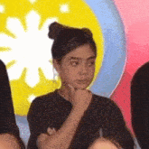 a girl with a bun on her head is sitting in front of a crowd of people .