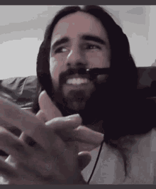a man with long hair and a beard wearing a headset is smiling .