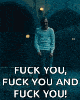 a man is standing in front of a building with the words `` fuck you , fuck you and fuck you '' written on it .