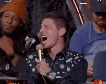a man is singing into a microphone in a crowd of people .