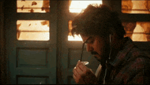 a man in a plaid shirt is smoking a cigarette and listening to music .