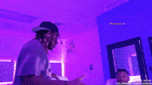 a man wearing a champs shirt stands in front of a purple background