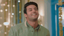 a man in a green jacket is smiling and looking at the camera