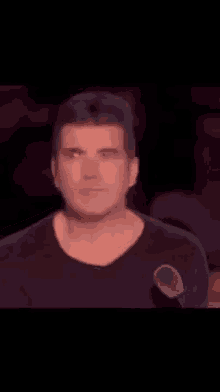 a man in a black shirt is standing in front of a microphone and making a face