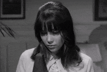 a black and white photo of a woman in a suit and tie .