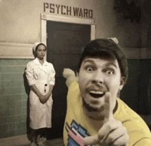 a man giving a thumbs up in front of a psych ward sign