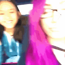 two girls with pink hair are sitting in a car and smiling .