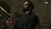 a man with a beard is clapping his hands in front of a hbo logo