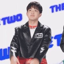 a young boy wearing a black leather jacket has a name tag with the name trie on it