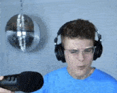 a man wearing headphones and glasses is talking into a microphone .