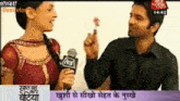 a man is holding a flower and talking to a woman on a television screen