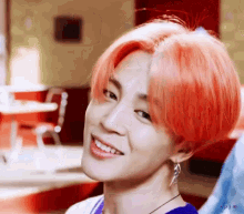 a young man with bright red hair is smiling in a restaurant .