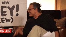 a man sits in front of a sign that says " ey "