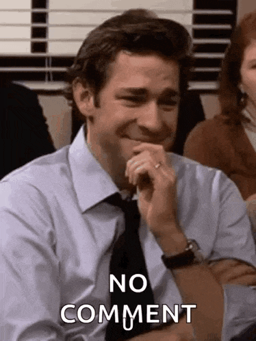 a man in a suit and tie is laughing and saying `` no comment '' while sitting at a table .