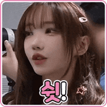 a girl is holding a camera in her hand and looking at the camera .