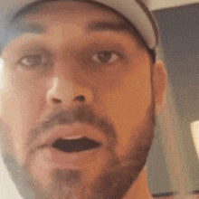 a man with a beard wearing a hat and a white shirt