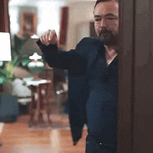 a man in a suit is standing in a living room holding a gun .